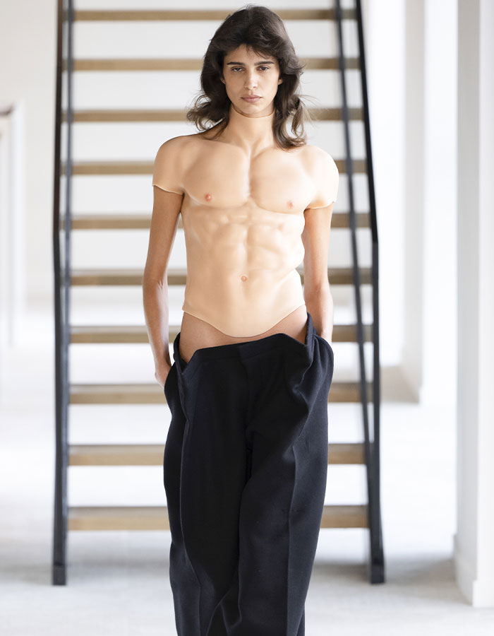 Fashion model wearing bold male top imitating female bare chest at Paris Fashion Week.