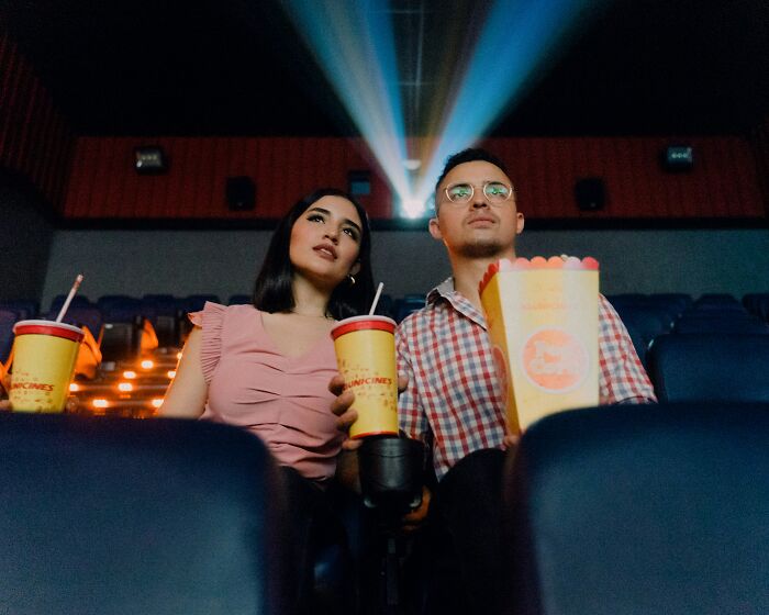 Couple enjoying a movie with popcorn and drinks, representing valuable memberships experience.