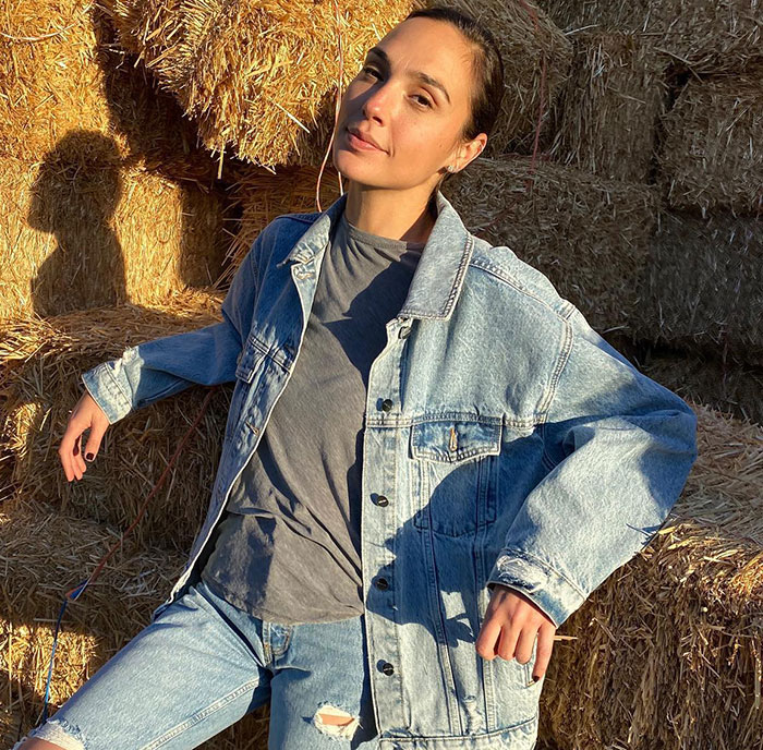 Person in a denim jacket and jeans sitting on hay bales; related to Disney and Snow White controversy.