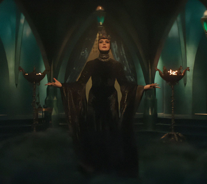 A character in a dark, dramatic setting, surrounded by mystical green light, related to Disney's 'Snow White' premiere.