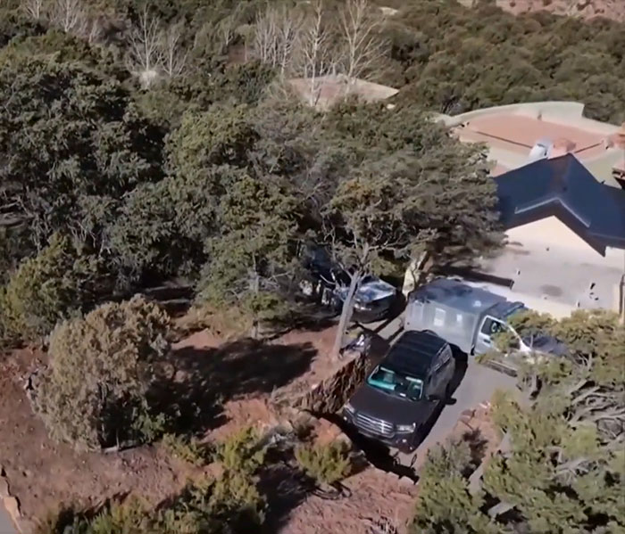 Aerial view of a house surrounded by trees with parked cars, related to Gene Hackman's passing.