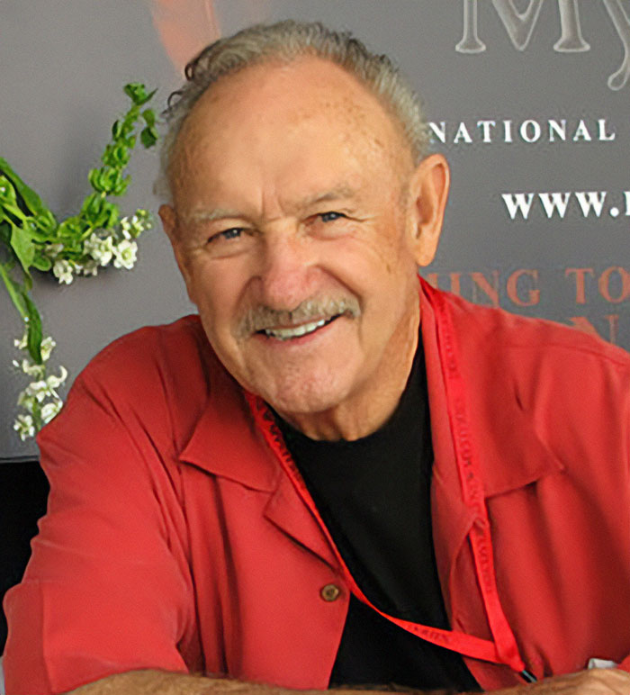 Man in a red shirt smiling at a public event, related to medical examiner's theory on "broken heart-type thing.