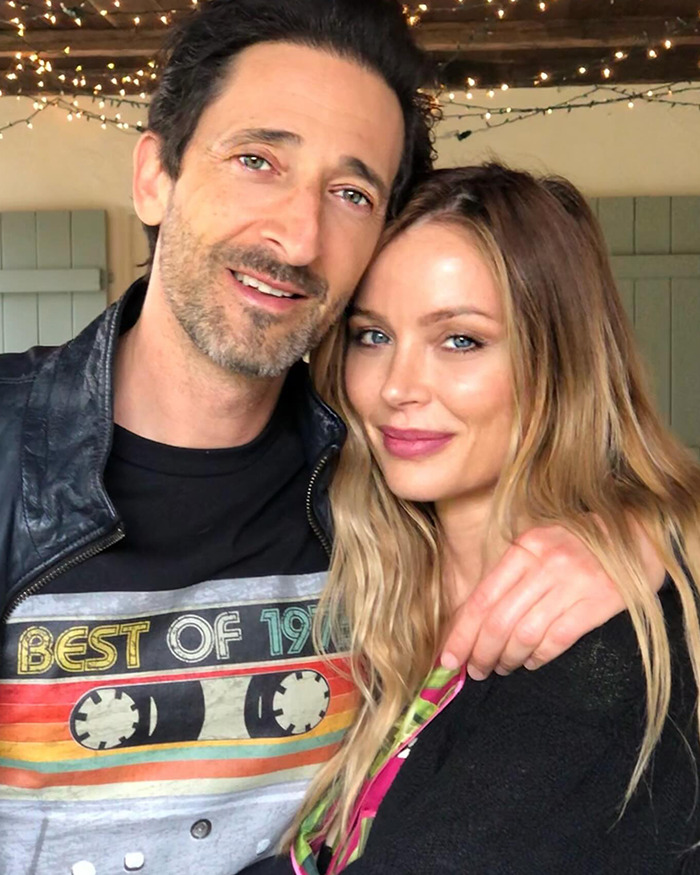 Georgina Chapman and Adrien Brody smiling together for a selfie.