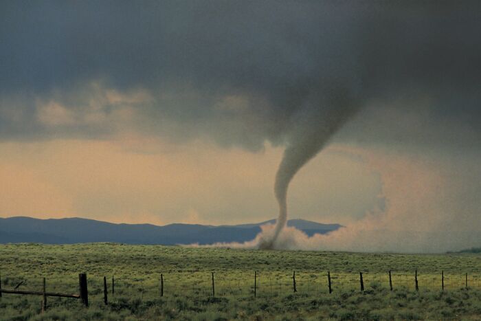 A tornado touches down in a vast field, illustrating random world facts and powerful natural events.