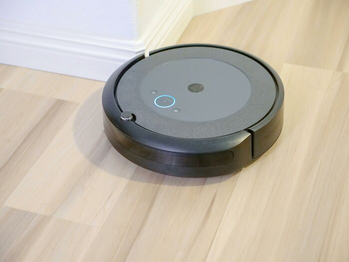 Robot vacuum on a wooden floor, showcasing a cleaning hack for efficient home maintenance.