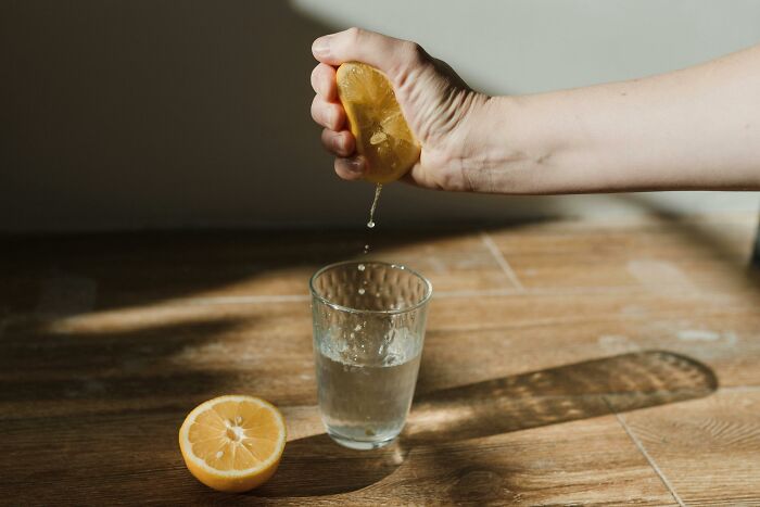 Squeezing lemon juice into a glass, showcasing a lesser-known cleaning hack.