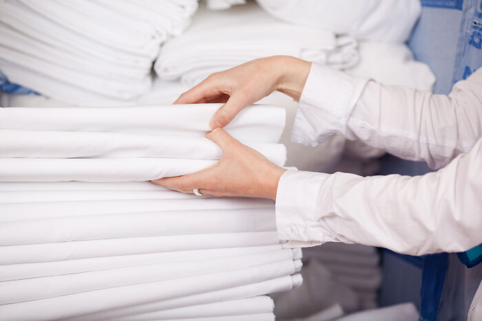 Hands neatly stacking white linens, showcasing an effective cleaning hack.