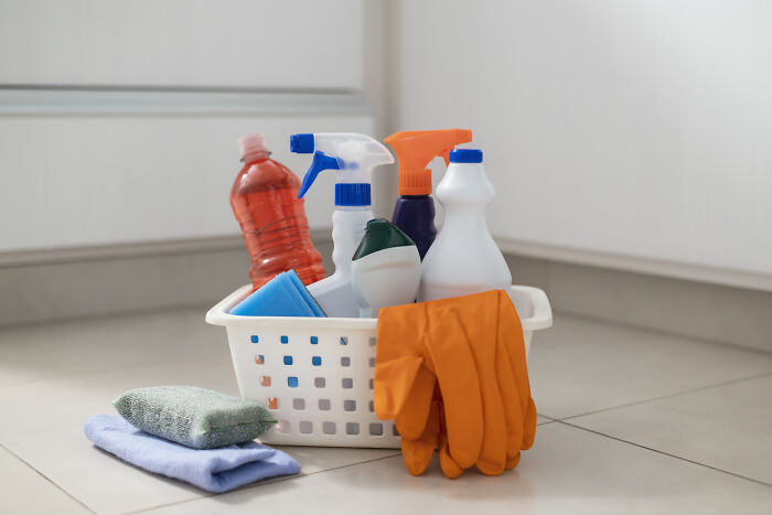 Basket with cleaning supplies and gloves on the floor, illustrating lesser-known cleaning hacks.