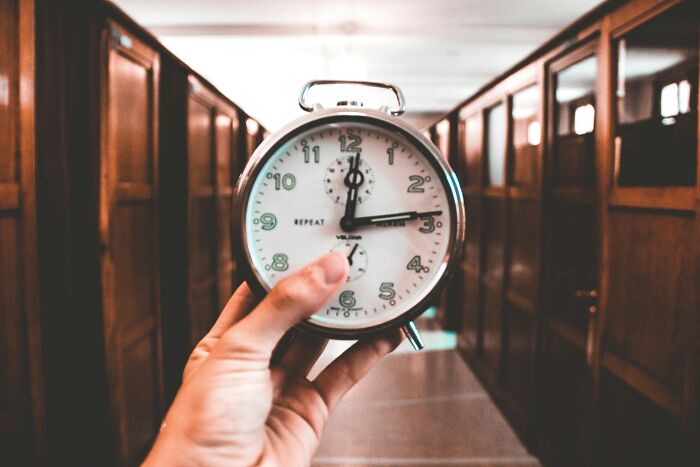 Hand holding a clock in a corridor, showcasing a lesser-known cleaning hack for efficient time management.