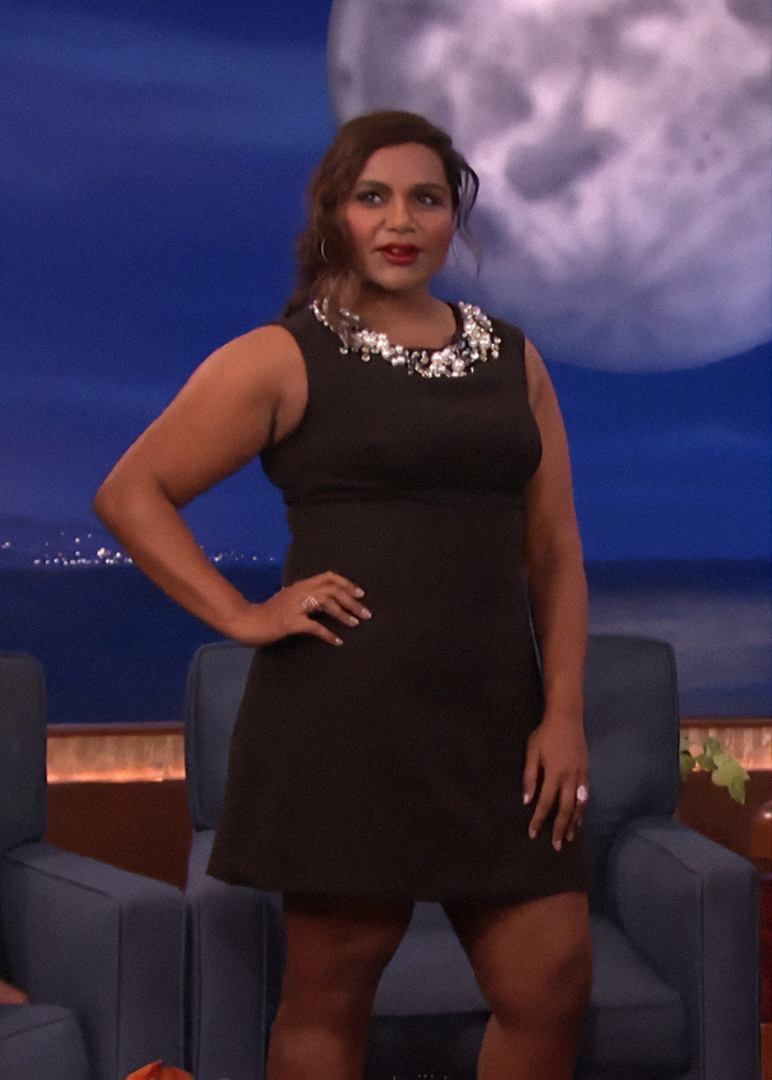 A person in a black dress on a talk show set, reflecting changing beauty standards in Hollywood.