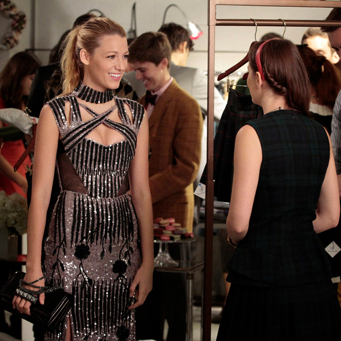 Two women engaged in conversation at a social event, one wearing a sparkling dress.