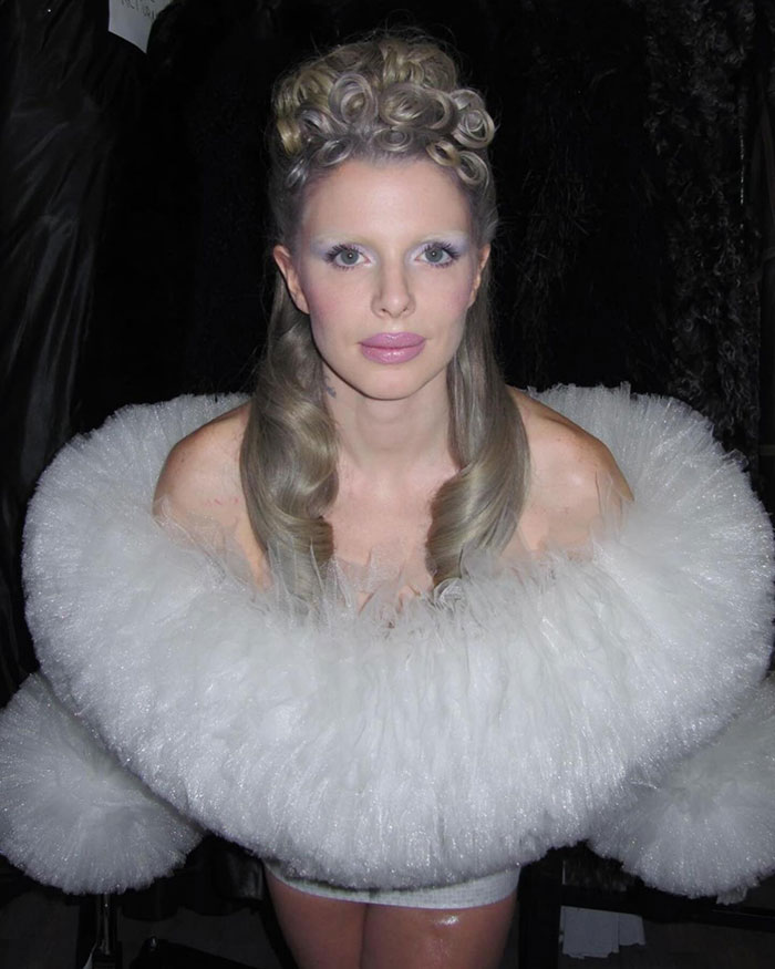 Woman in a white, ruffled gown with styled hair at an event, replicating Bianca Censori's look.