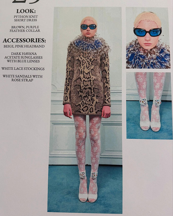 Trans model debuts at Paris Fashion Week in python dress, feather collar, lace stockings, and blue lens sunglasses.