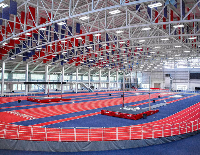 Indoor track stadium with red and blue lanes, featuring high ceilings and ample space for athletic events.