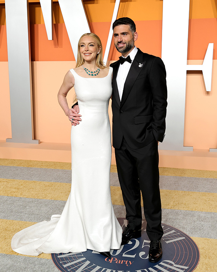 A woman in a white dress and a man in a tuxedo at the Oscars after-party.