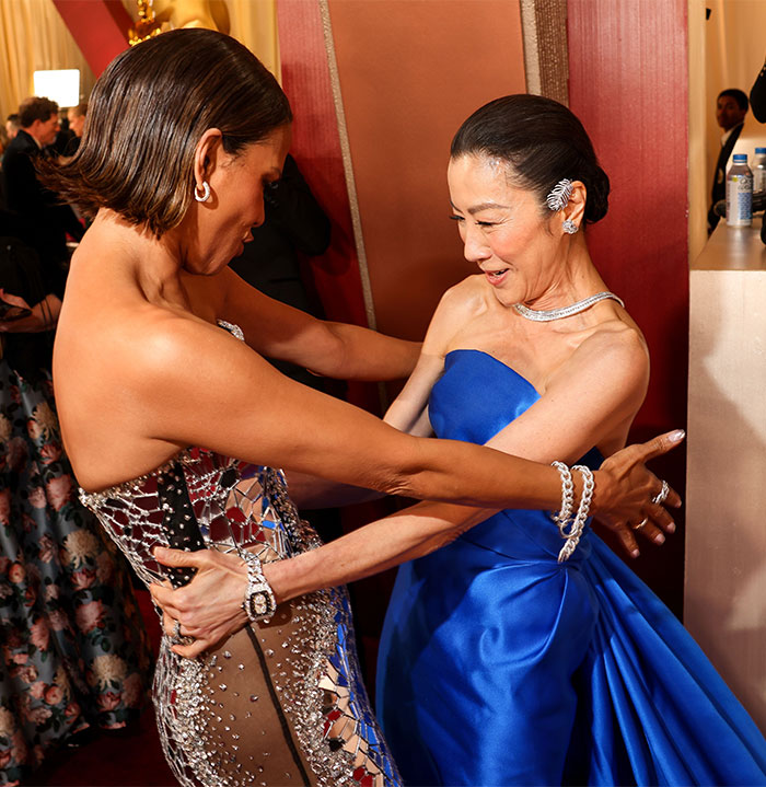 Two women joyfully embrace in a vibrant setting, showcasing a behind-the-scenes moment at Oscars 2025.