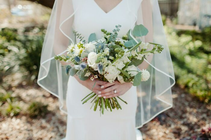 Bride in white holding a bouquet, symbolizing wedding moments and guest objections.