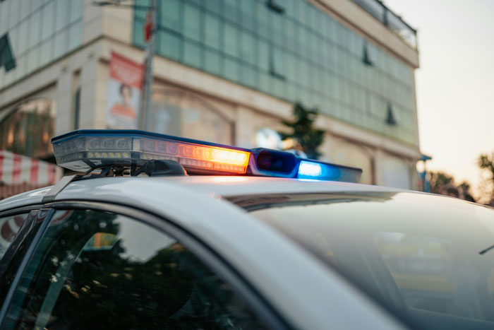 Police car with flashing lights near a building, related to woman who vanished without a trace.