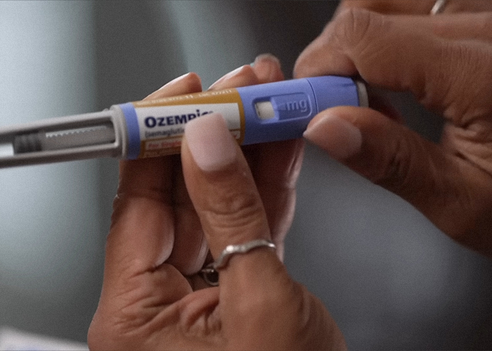 Hands holding an Ozempic pen, highlighting its use in Hollywood and sparking debate over beauty standards.