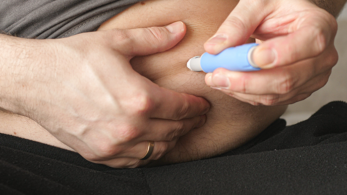 Person injecting medication, highlighting Ozempic&rsquo;s impact on Hollywood beauty standards.