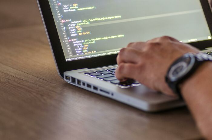 Person typing code on a laptop, working on an article about cool topics for reading.