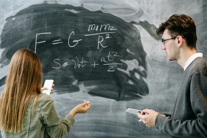 Two people solving complex equations on a chalkboard, illustrating cool Wikipedia articles on science topics.