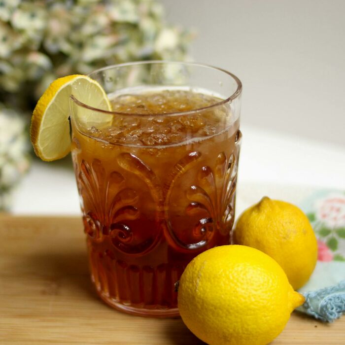 Glass of iced tea with lemon slice and whole lemons, capturing a fresh perspective on world flavors.