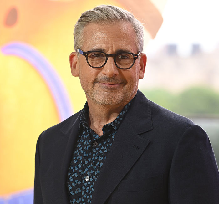 A man smiling, wearing glasses and a dark suit, attending an event related to helping LA fire victims.