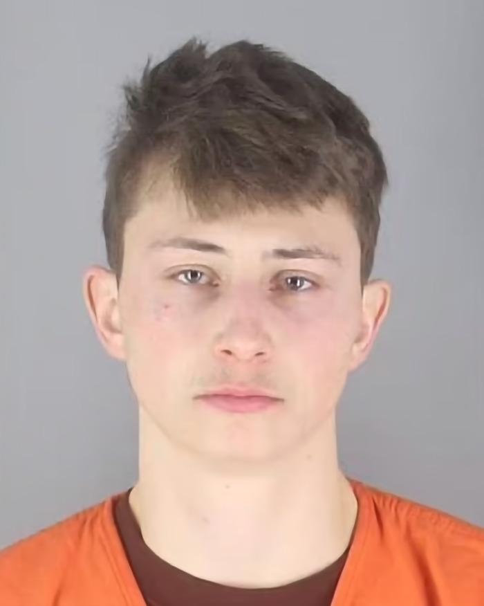 Young man in orange outfit, associated with lenient prosecutor case, neutral expression, gray background.