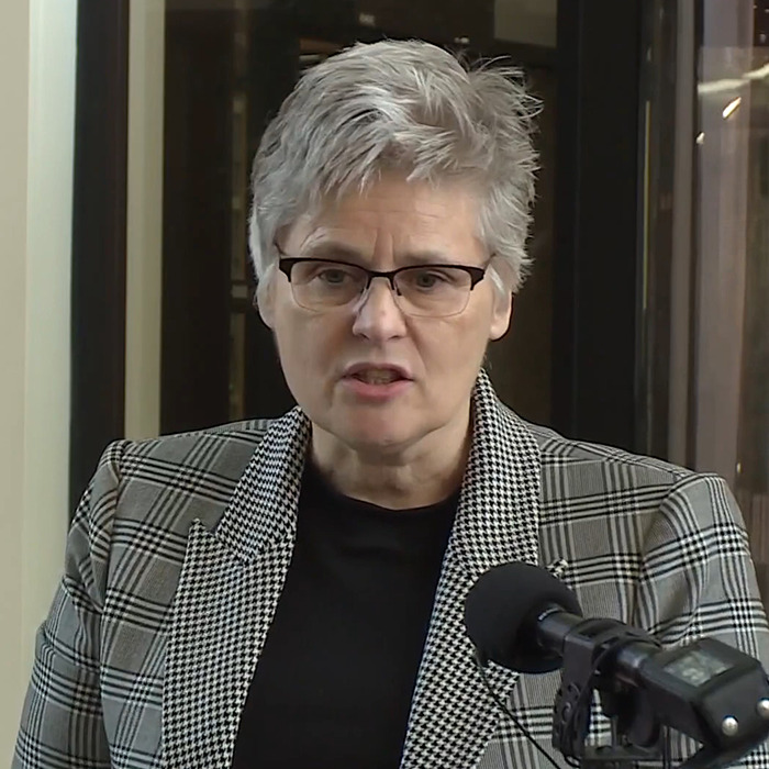 Woman in a plaid jacket speaking into a microphone, discussing a teen offender case.