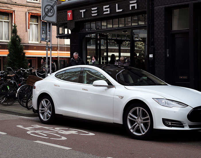 White Tesla parked in front of a Tesla station, highlighting charging station dynamics.