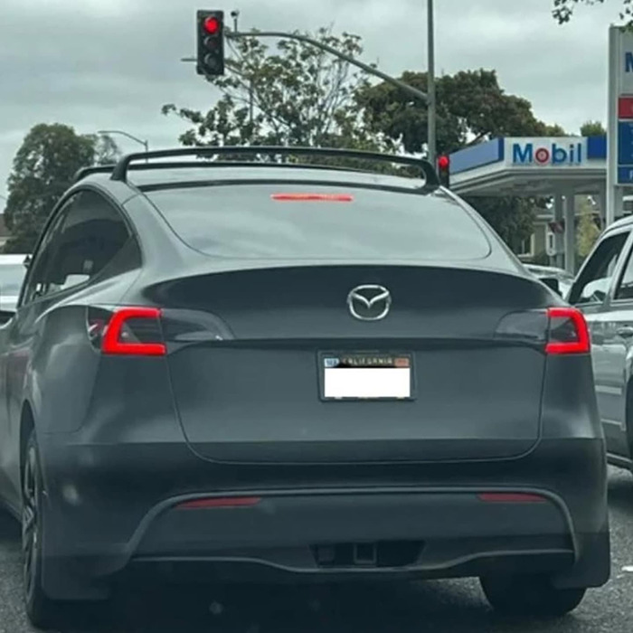 Tesla with changed logo at a traffic light, reflecting concerns over vandalism in Elon Musk controversy.