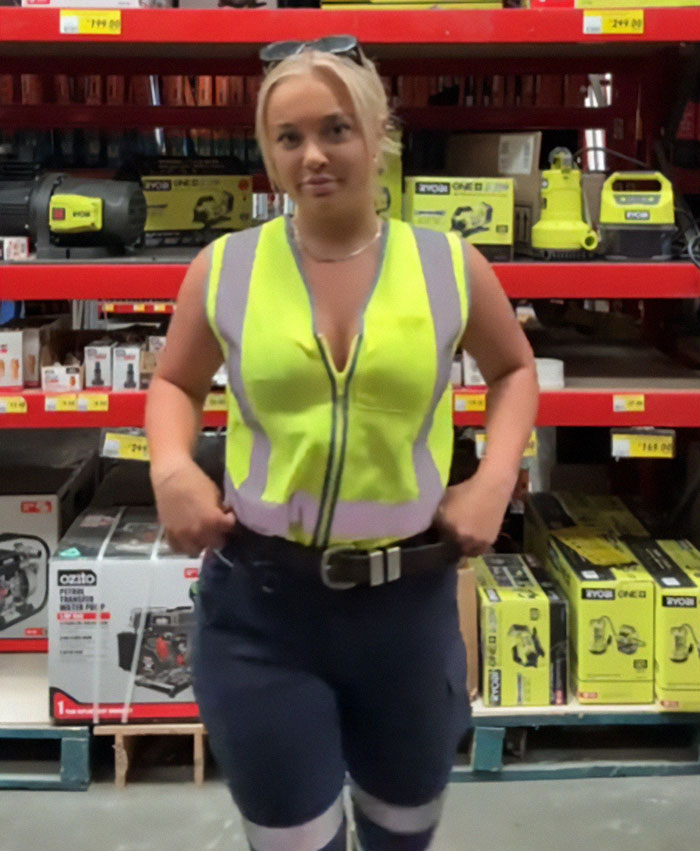 Woman in a high-visibility vest standing in a hardware store, representing bikini tradie rights discussion.