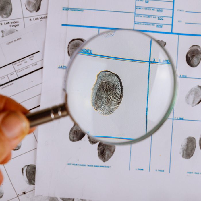 Fingerprint under a magnifying glass on investigation documents related to a girl found after vanishing for 26 years.