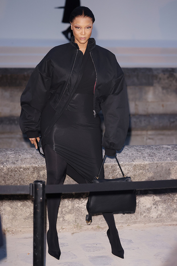 Asistente de la Semana de la Moda con atuendo negro, mostrando piel tensa en el evento de París.